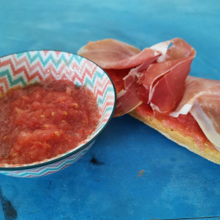 Pão torrado com tomate, presunto e azeite de oliva.