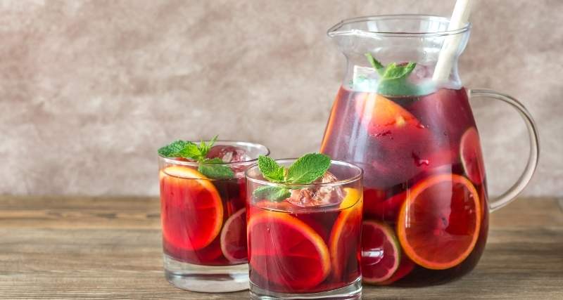 Um jarro e dois copos com Sangria de fruta espanhola.